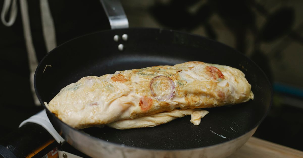 Złożony omlet z warzywami smaży się na patelni na niskim ogniu.